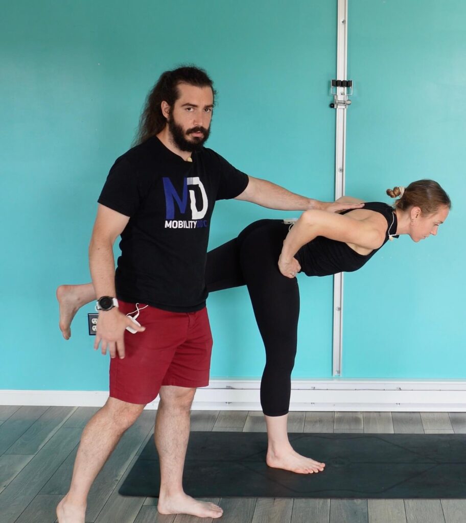 Dr. Chloe balancing on her right foot with her left leg extended behind her in a hip hinge to do a romanian deadlift the final part of this glute activation exericse